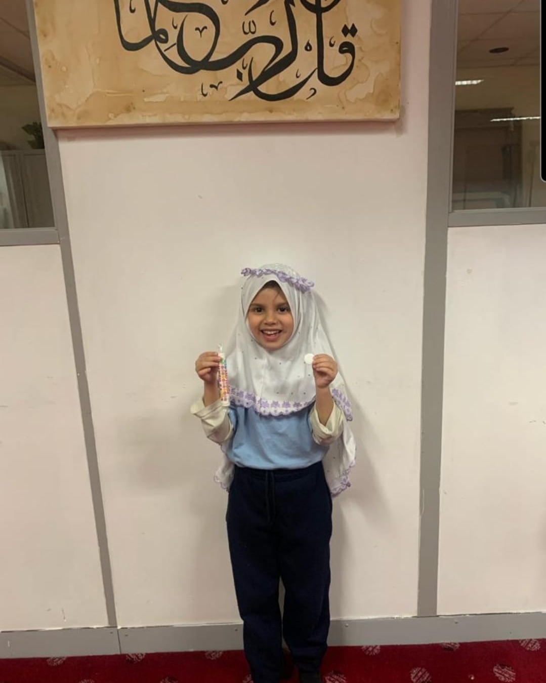 Zoya holding her white Read and Rise badge